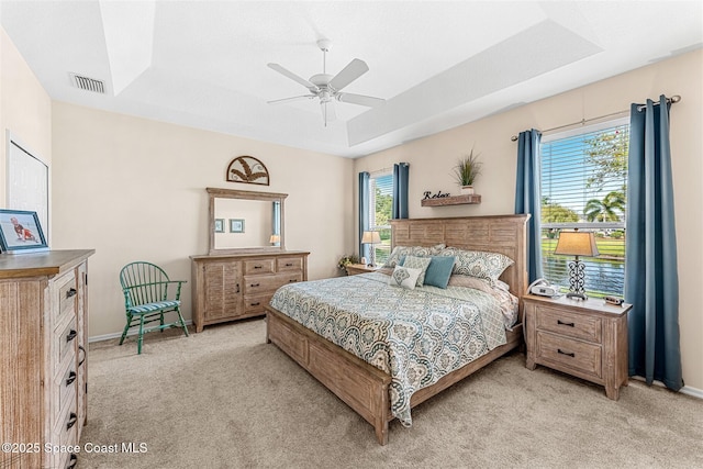 bedroom with baseboards, visible vents, a raised ceiling, and light carpet