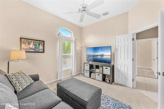carpeted living area featuring tile patterned flooring, vaulted ceiling, ceiling fan, baseboards, and visible vents