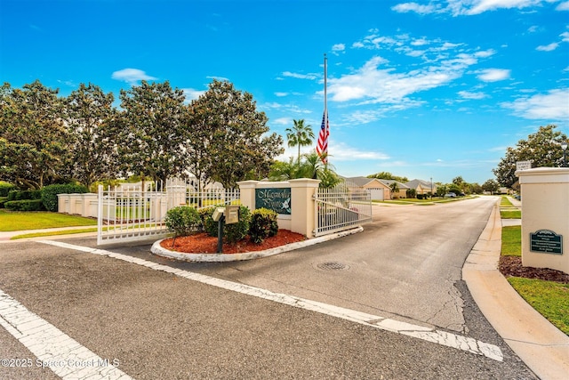 view of road featuring a residential view, curbs, a gated entry, and a gate