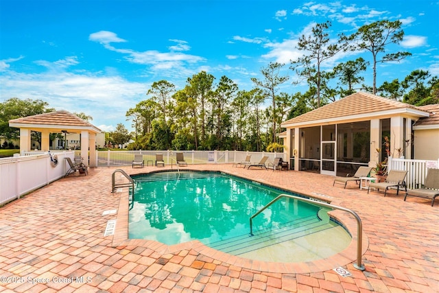 community pool with fence, ceiling fan, a gazebo, a patio, and a sunroom