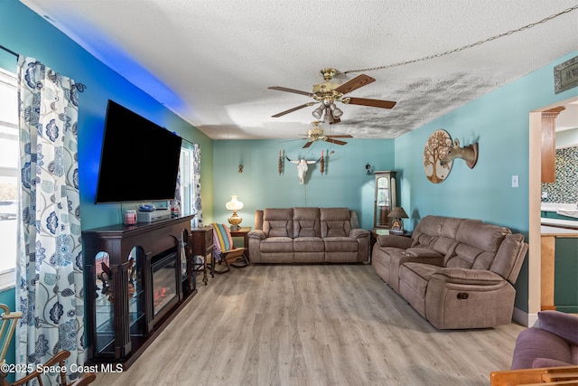 living room with ceiling fan, wood finished floors, and a textured ceiling