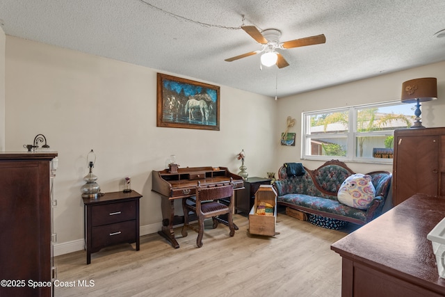 home office with ceiling fan, baseboards, light wood-style floors, and a textured ceiling