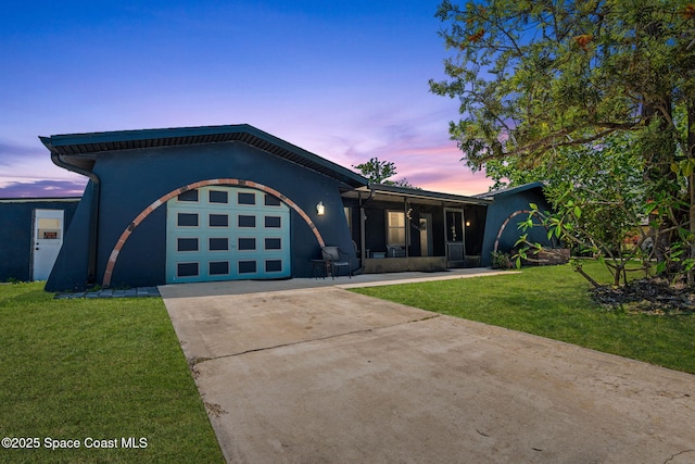 view of front of house featuring concrete driveway, stucco siding, a yard, and a garage