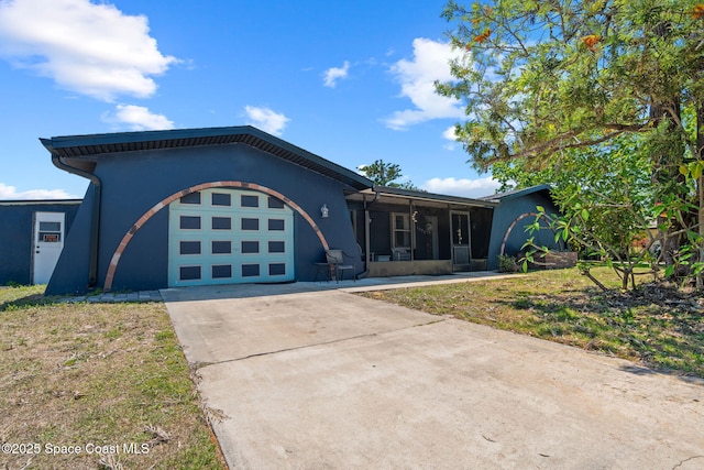 view of front facade with stucco siding, an attached garage, a sunroom, and driveway