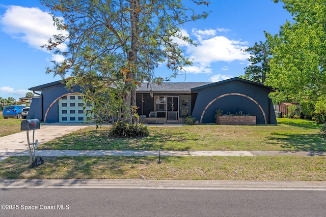 ranch-style home featuring concrete driveway, a front lawn, an attached garage, stucco siding, and a sunroom
