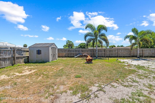 view of yard featuring an outbuilding, a shed, a fenced backyard, and an outdoor fire pit