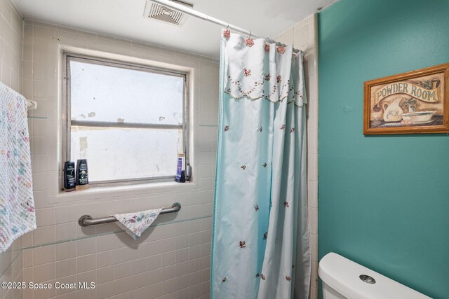 bathroom with visible vents, a shower with shower curtain, and toilet
