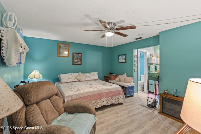 bedroom with a textured ceiling, visible vents, wood finished floors, ceiling fan, and connected bathroom