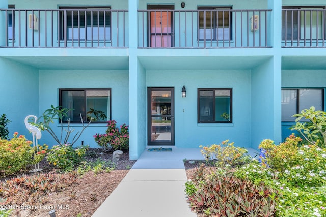 entrance to property featuring a balcony and stucco siding