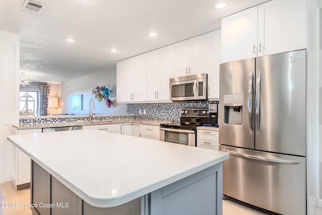 kitchen with light countertops, backsplash, visible vents, a sink, and appliances with stainless steel finishes