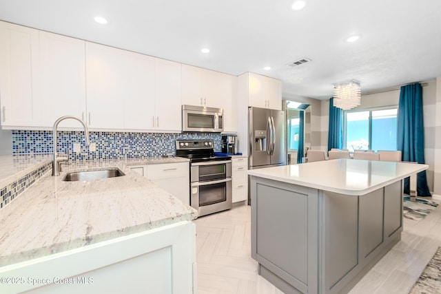 kitchen with stainless steel appliances, a sink, tasteful backsplash, visible vents, and a kitchen island