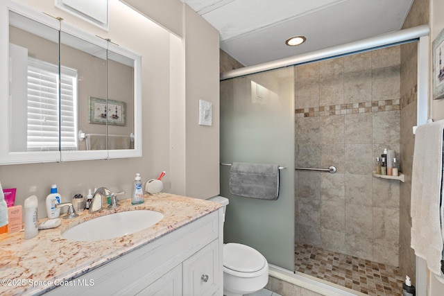 bathroom featuring vanity, toilet, and a stall shower