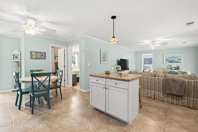 kitchen featuring crown molding, a ceiling fan, open floor plan, a kitchen island, and visible vents