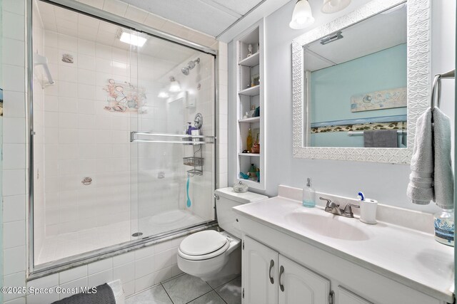 full bath with vanity, toilet, tile patterned floors, built in shelves, and a stall shower