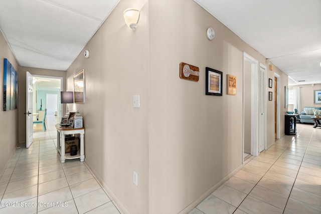 corridor featuring light tile patterned floors and baseboards