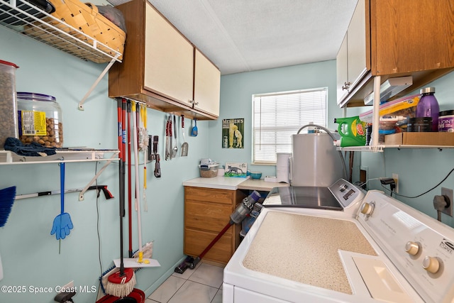 laundry area featuring light tile patterned floors, baseboards, cabinet space, and washer and dryer
