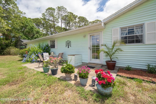 back of house with a lawn and a patio
