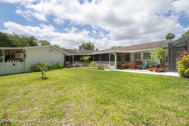 back of property with a lawn, fence, and a sunroom