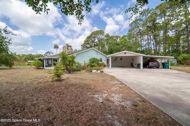 view of side of property with a sunroom, a carport, and concrete driveway