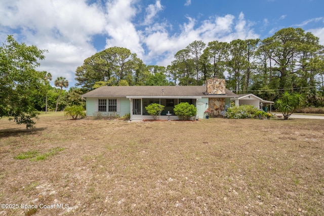 ranch-style house with a chimney, a sunroom, and a front yard