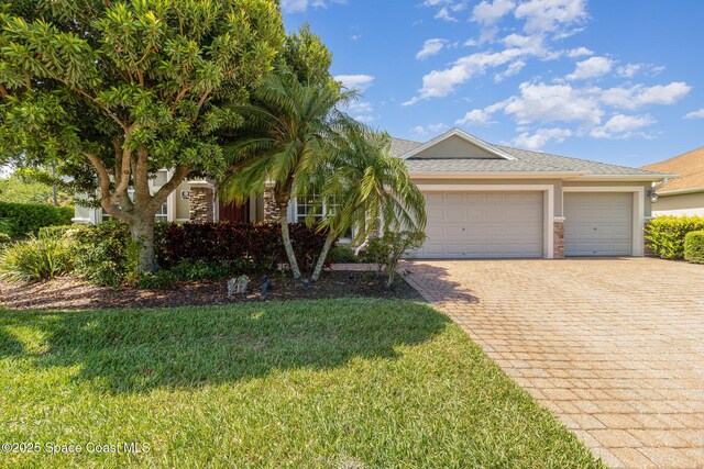 3196 Quint Dr, Melbourne, FL 32940 - view of front facade featuring decorative driveway, stucco siding, a garage, a front yard, and stone siding
