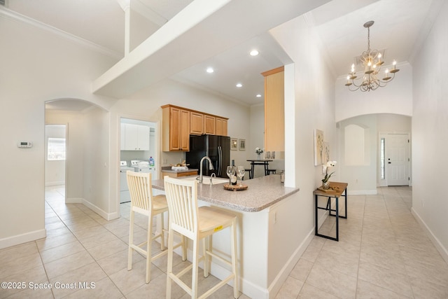 3196 Quint Dr, Melbourne, FL 32940 - kitchen featuring arched walkways, freestanding refrigerator, crown molding, separate washer and dryer, and light tile patterned floors