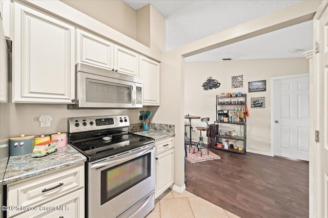 6280 Golfview Ave, Cocoa, FL 32927 - kitchen featuring wood finished floors, light stone countertops, a textured ceiling, white cabinets, and appliances with stainless steel finishes