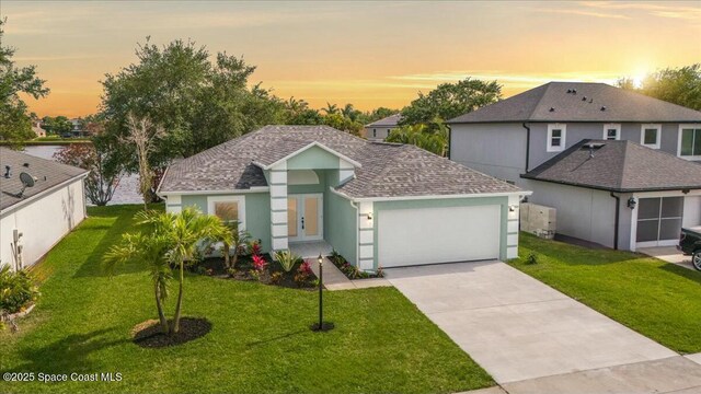 3871 La Flor Dr, Rockledge, FL 32955 - view of front of home with driveway, a garage, a shingled roof, a yard, and stucco siding
