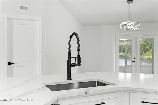 3871 La Flor Dr, Rockledge, FL 32955 - kitchen with light stone counters, a sink, french doors, white cabinets, and visible vents