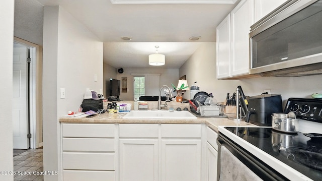 3050 Sir Hamilton Cir Unit 2, Titusville, FL 32780 - kitchen featuring electric stove, stainless steel microwave, a sink, white cabinets, and a peninsula