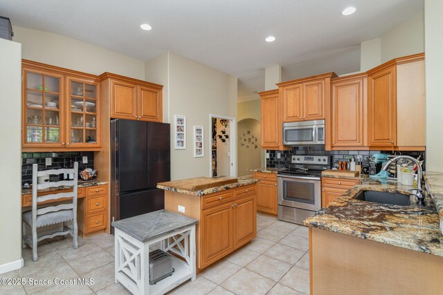 439 Gardendale Cir SE, Palm Bay, FL 32909 - kitchen featuring a sink, decorative backsplash, arched walkways, appliances with stainless steel finishes, and light stone countertops