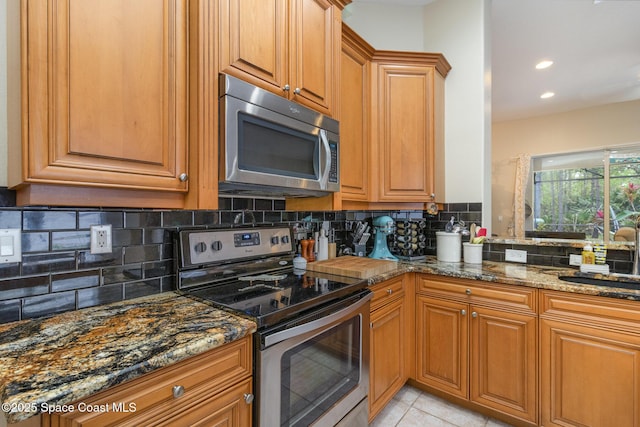 439 Gardendale Cir SE, Palm Bay, FL 32909 - kitchen featuring dark stone counters, tasteful backsplash, a sink, brown cabinets, and appliances with stainless steel finishes