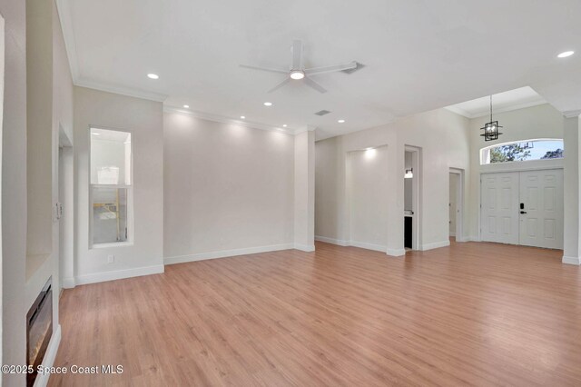 2742 Fling Ave SE, Palm Bay, FL 32909 - unfurnished living room with ceiling fan with notable chandelier, light wood-style floors, a fireplace, baseboards, and ornamental molding