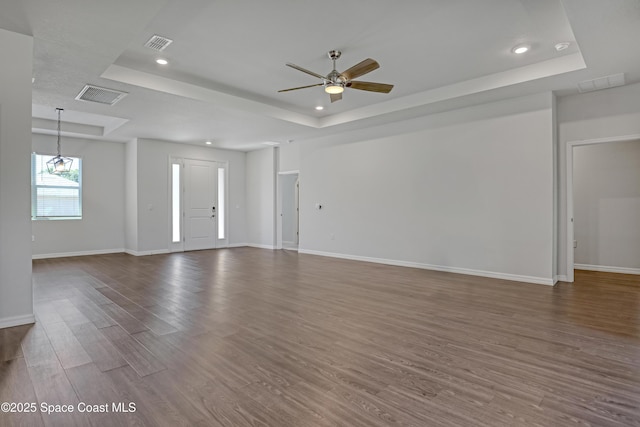 unfurnished living room featuring dark wood-style flooring, visible vents, recessed lighting, ceiling fan, and a raised ceiling