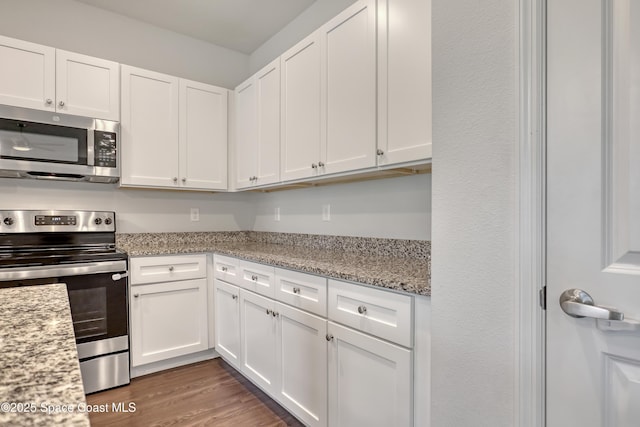 kitchen with white cabinets, wood finished floors, light stone countertops, and appliances with stainless steel finishes