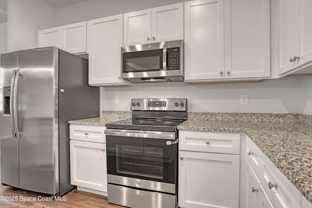 kitchen with white cabinets, wood finished floors, and stainless steel appliances