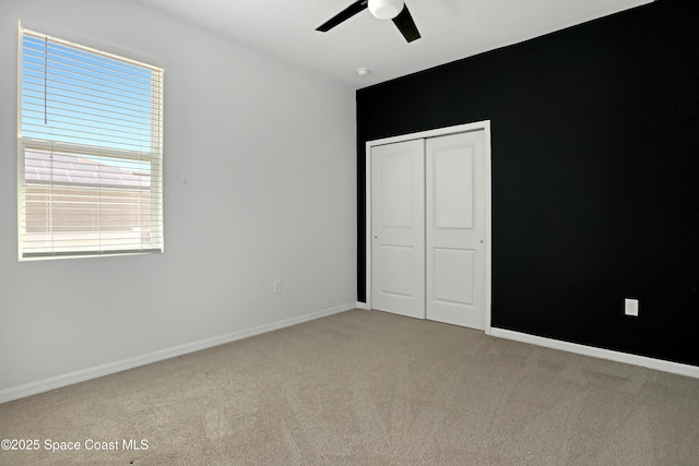 unfurnished bedroom with light carpet, a ceiling fan, baseboards, and a closet