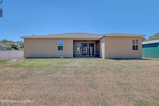rear view of property with fence, a lawn, a ceiling fan, and stucco siding