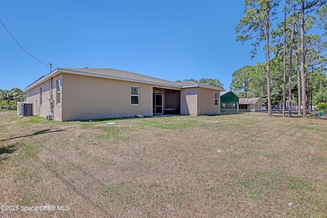 rear view of property with a lawn, stucco siding, and fence