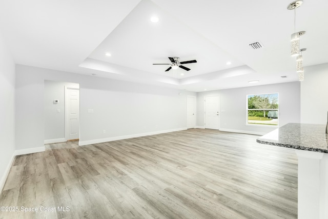 unfurnished living room featuring recessed lighting, a tray ceiling, visible vents, light wood-style floors, and ceiling fan