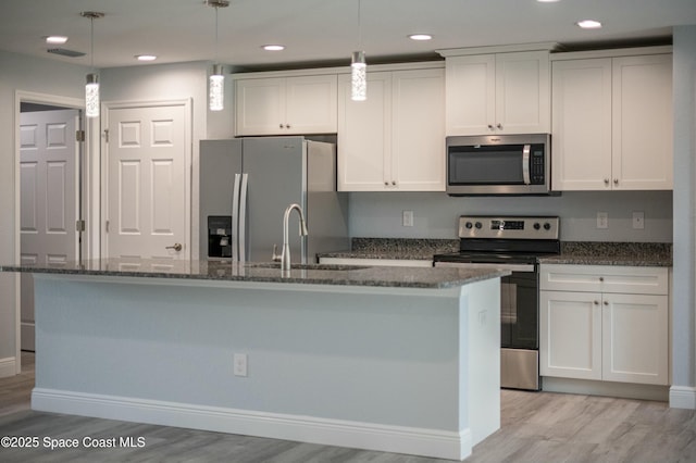 kitchen featuring visible vents, a kitchen island with sink, light wood-style flooring, appliances with stainless steel finishes, and white cabinetry