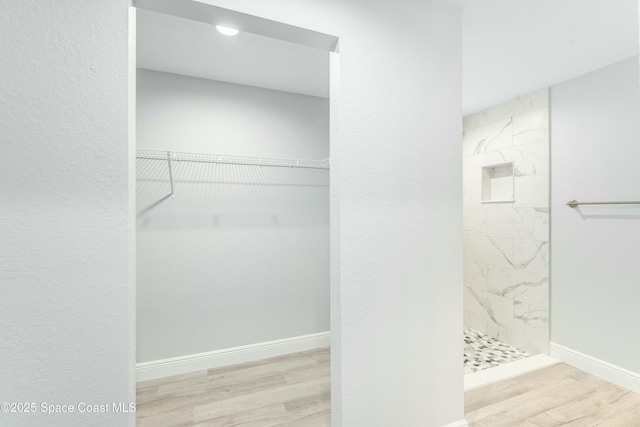 bathroom with a marble finish shower, baseboards, recessed lighting, wood finished floors, and a walk in closet