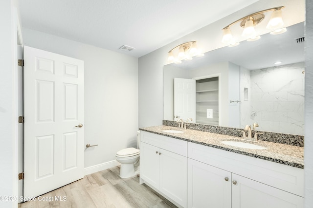 bathroom with wood finished floors, a sink, and visible vents