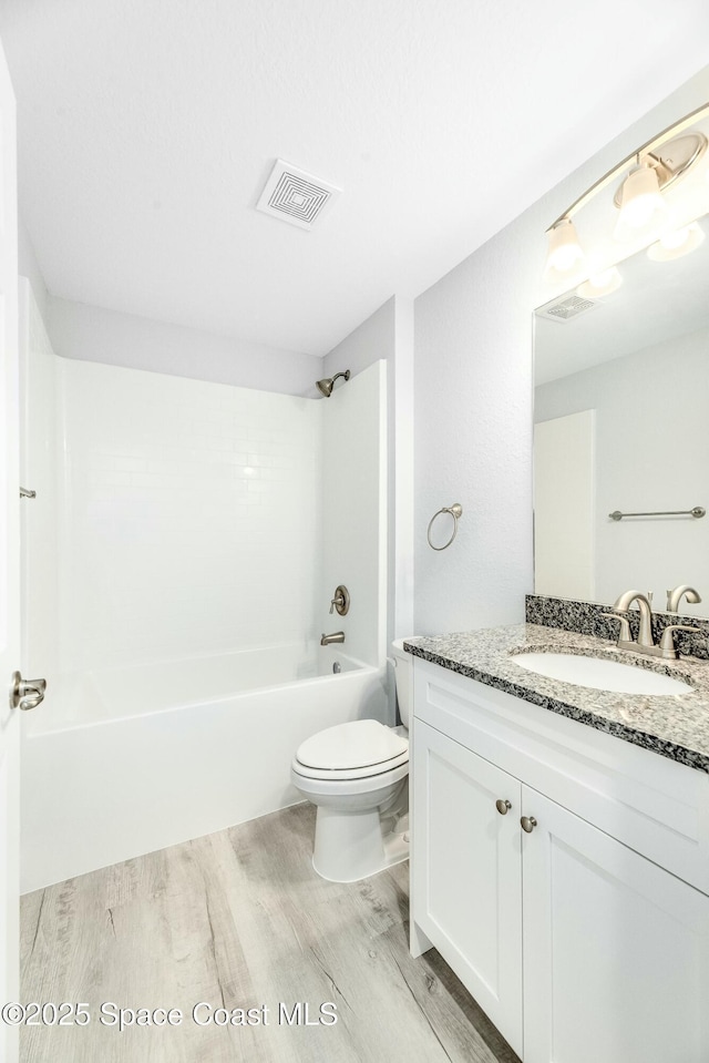 bathroom with wood finished floors, vanity, shower / washtub combination, toilet, and visible vents