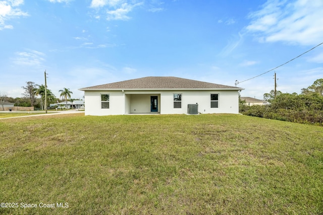 rear view of property featuring stucco siding, a lawn, roof with shingles, and central AC unit