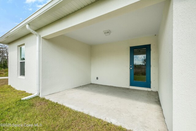 view of exterior entry with a patio area and stucco siding