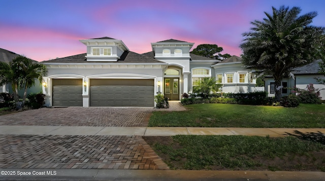 3630 Kite St, Titusville, FL 32796 - view of front facade with stucco siding, a lawn, decorative driveway, and a garage