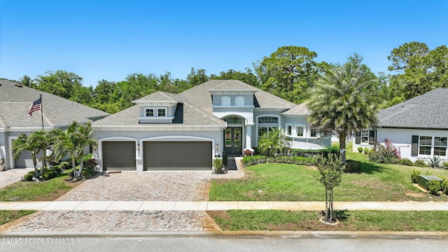 3630 Kite St, Titusville, FL 32796 - french country style house with a garage, a shingled roof, a front yard, stucco siding, and decorative driveway