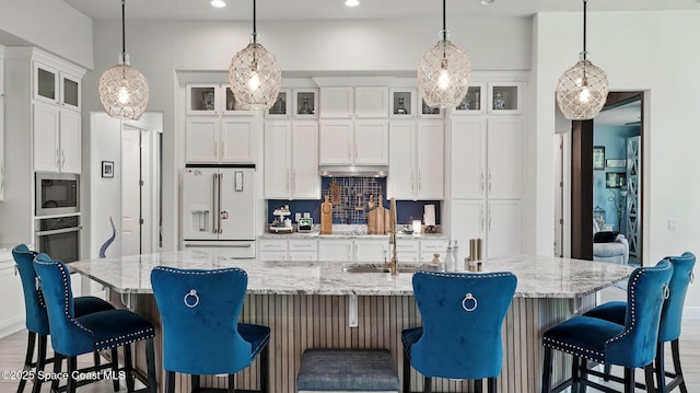 3630 Kite St, Titusville, FL 32796 - kitchen featuring a large island with sink, oven, built in microwave, backsplash, and white fridge with ice dispenser