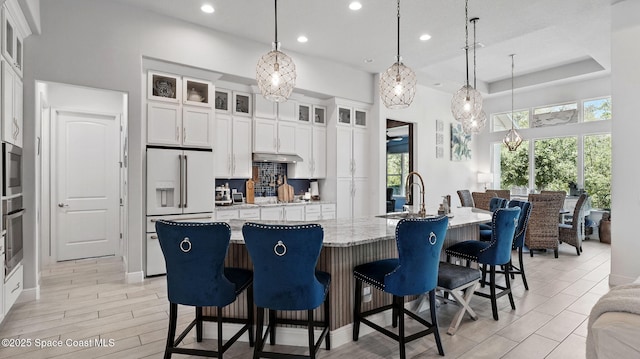3630 Kite St, Titusville, FL 32796 - kitchen featuring white cabinets, recessed lighting, high end fridge, a breakfast bar, and under cabinet range hood